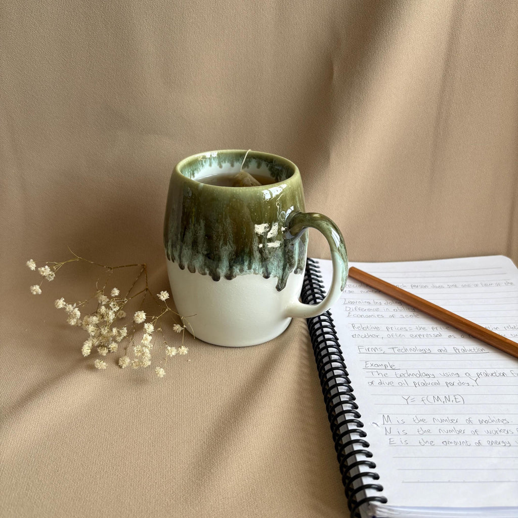 Grey & White Drip Glaze Stoneware Mug next to a notebook and pencil, showcasing its unique drip glaze design.